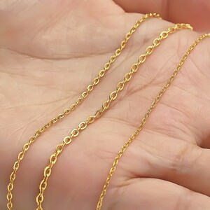 May include: Three gold chains of different lengths and thicknesses, displayed on a hand.