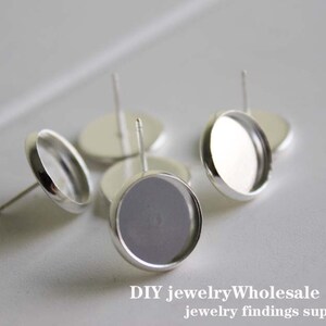May include: Silver earring settings with round, clear glass cabochons. The settings have a post and a flat back.