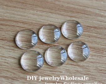 May include: Six clear glass cabochons, round and smooth, arranged on a light brown wooden surface. DIY jewelry wholesale jewelry findings supplies.