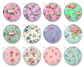 Puede incluir: Una colección de doce cabujones redondos de vidrio con diseños florales. Los cabujones presentan varios colores, incluyendo rosa, morado, azul y verde, con diferentes patrones florales. Cada cabujón mide aproximadamente 2,5 cm de diámetro.