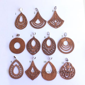 May include: Eleven pairs of wooden earrings with intricate laser cut designs. The earrings are in various shapes, including teardrop, circle, and diamond. The earrings are all brown and have silver posts.