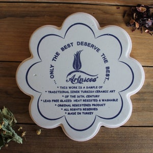 May include: White ceramic tile with a blue floral design and the text "...ONLY THE BEST DESERVE THE BEST... Artnicea" and "* THIS WORK IS A SAMPLE OF * TRADITIONAL IZNIK TURKISH CERAMIC ART * OF THE 16TH. CENTURY * LEAD FREE GLAZED HEAT RESISTED & WASHABLE * ORGINAL REGISTERED PRODUCT * ALL RIGHTS RESERVED * MADE IN TURKEY"