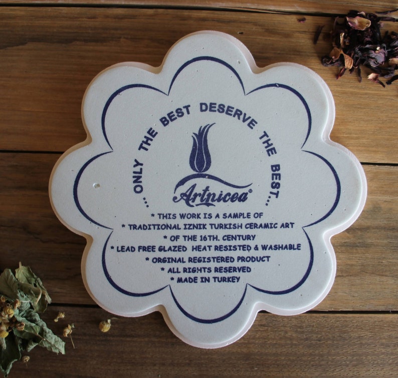 May include: White ceramic tile with a blue floral design and the text "...ONLY THE BEST DESERVE THE BEST... Artnicea" and "* THIS WORK IS A SAMPLE OF * TRADITIONAL IZNIK TURKISH CERAMIC ART * OF THE 16TH. CENTURY * LEAD FREE GLAZED HEAT RESISTED & WASHABLE * ORGINAL REGISTERED PRODUCT * ALL RIGHTS RESERVED * MADE IN TURKEY"
