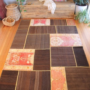 May include: A patchwork rug with a brown background and colourful floral patterns in shades of pink, red, and cream. The rug is made up of several smaller rugs sewn together.