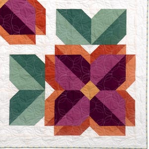 May include: A quilt featuring a floral pattern with geometric petals in shades of deep purple, magenta, and orange, accented by sage green leaves. The white background is stitched with a repeating circular pattern, and the edge has a thin floral border.