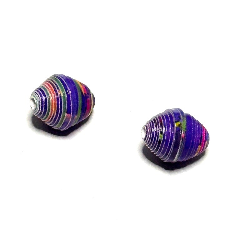 May include: Two purple and white paper beads with colorful patterns. The beads are rolled and have a spiral shape.