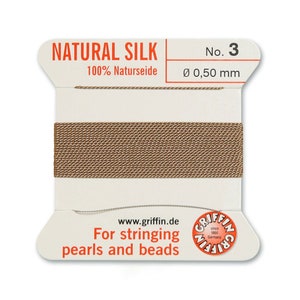 May include: A spool of natural silk thread for stringing pearls and beads. The spool is labelled "Natural Silk 100% Naturseide No. 3 &Oslash; 0,50 mm" and "www.griffin.de For stringing pearls and beads".