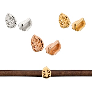 Peut inclure: Trois paires de fermoirs en métal en forme de feuille en argent, or et or rose. Les fermoirs sont présentés sur une sangle en cuir marron.