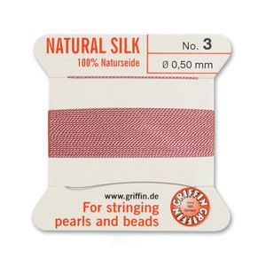 May include: A spool of natural silk thread for stringing pearls and beads. The spool is labelled "NATURAL SILK" and "100% Naturseide". The thread is a light pink colour and is 0.50 mm in diameter.