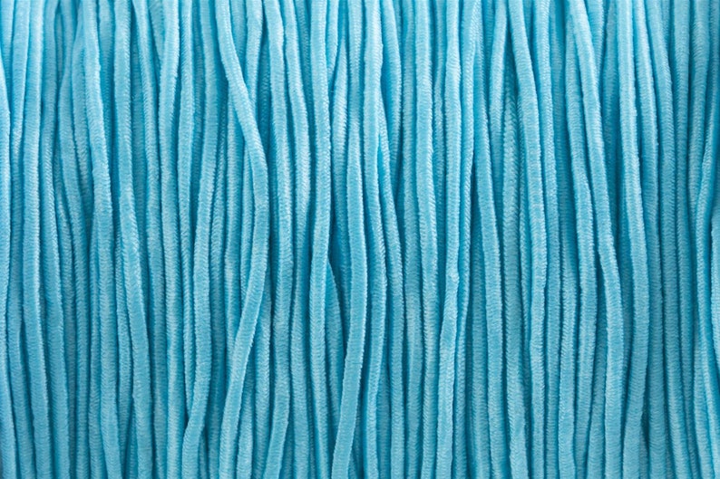 May include: A close-up of a bundle of light blue elastic cord. The cord is made of many thin strands that are twisted together.