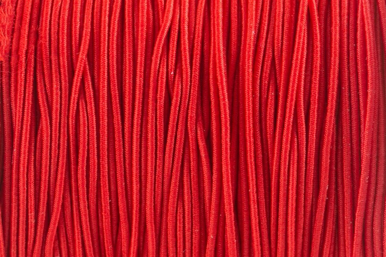 May include: A close-up of a bundle of red cords, all lined up in a parallel pattern.