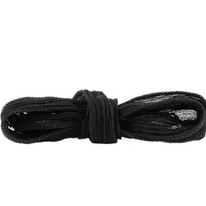 Puede incluir: Cordón elástico negro atado en un lazo. El cordón está hecho de un material suave y elástico y tiene una superficie ligeramente texturizada.