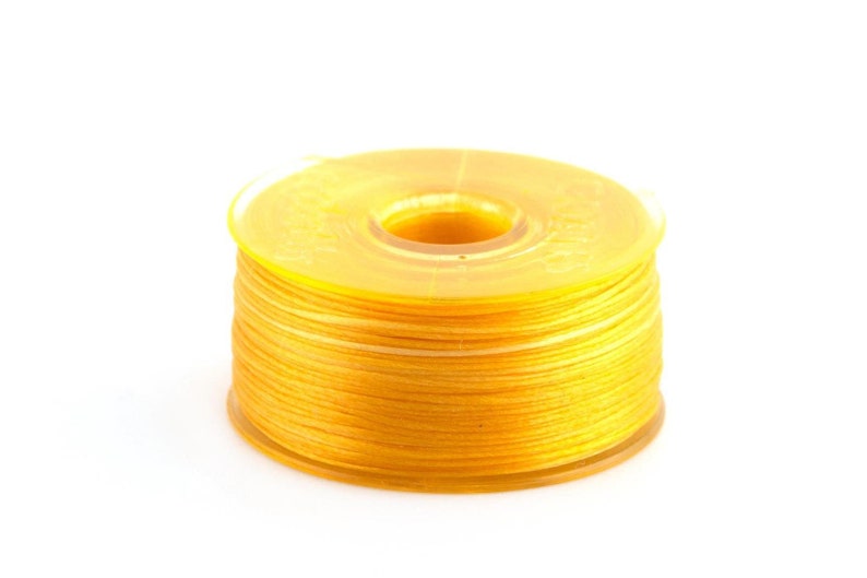 May include: A spool of bright yellow thread wound around a clear plastic bobbin.