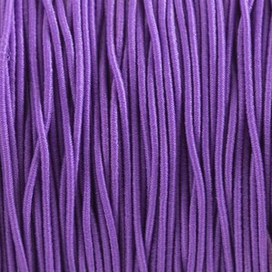 May include: A close-up of a bundle of purple elastic cord. The cord is tightly wound together, creating a textured surface.
