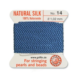 Puede incluir: Una bobina de hilo de seda natural azul para enhebrar perlas y cuentas. La etiqueta dice "NATURAL SILK 100% Naturseide No. 14 &Oslash; 1,02 mm www.griffin.de For stringing pearls and beads GRIFFIN"