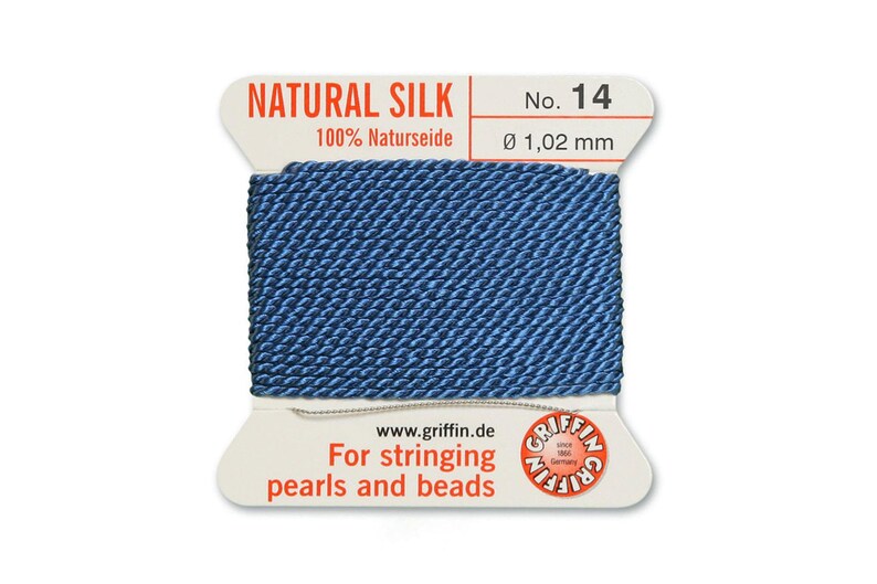 Puede incluir: Una bobina de hilo de seda natural azul para enhebrar perlas y cuentas. La etiqueta dice "NATURAL SILK 100% Naturseide No. 14 &Oslash; 1,02 mm www.griffin.de For stringing pearls and beads GRIFFIN"