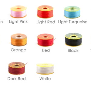 May include: Assortment of thread spools in various colours, including light green, light pink, light red, light turquoise, purple, olive, orange, red, black, turquoise, violet, dark red, and white.