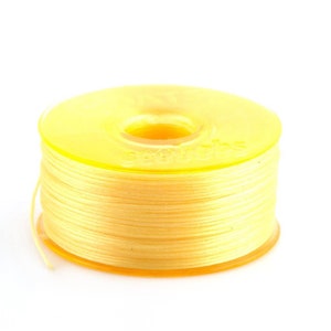 May include: A spool of yellow thread with a clear plastic bobbin.