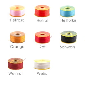 May include: A collection of spools of thread in various colours, including light green, pink, red, light blue, purple, olive, orange, red, black, turquoise, violet, burgundy, and white.