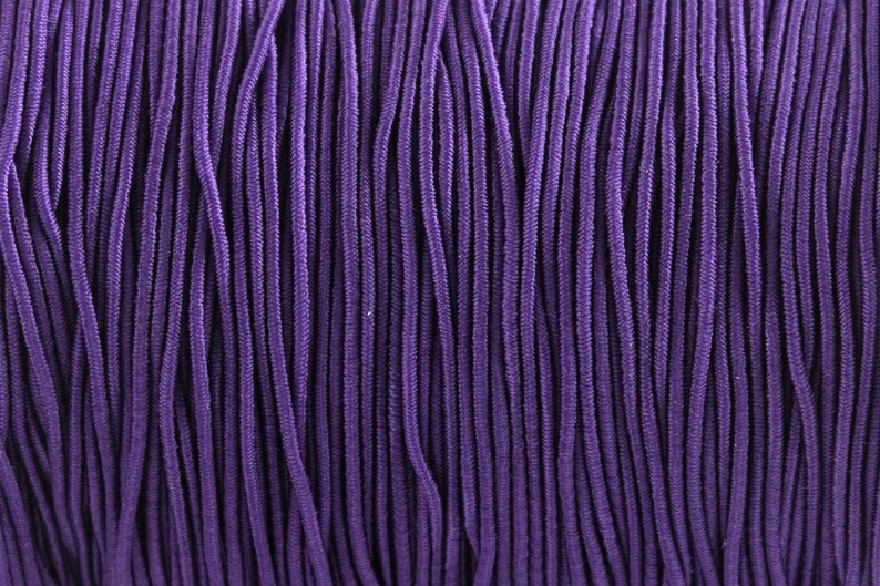 May include: A close-up of a spool of purple elastic cord. The cord is tightly wound and has a smooth, even texture.