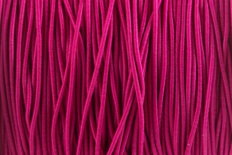 May include: Close-up of a bundle of pink elastic cord. The cord is tightly wound together, creating a smooth, textured surface.