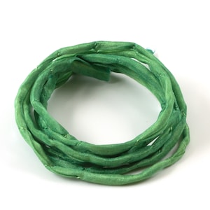 May include: A coil of green silk ribbon, ideal for crafting and decorating.