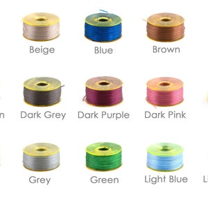 May include: A collection of 15 spools of thread in various colours, including apricot, beige, blue, brown, dark blue, dark brown, dark grey, dark purple, dark pink, yellow, gold, grey, green, light blue, and light brown.