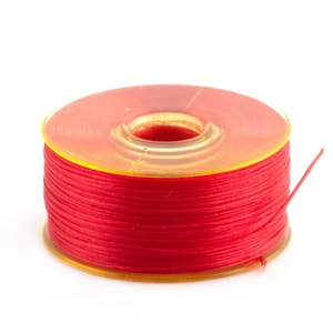 May include: A spool of red thread wound around a clear plastic bobbin.