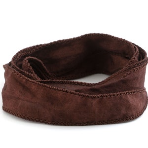 Può includere: Un nastro di raso marrone con un bordo cucito, arrotolato in un cerchio.