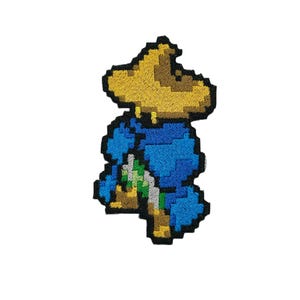 May include: Embroidered patch of a pixelated character wearing a yellow hat and blue clothing. The character is holding a green object in their hand.