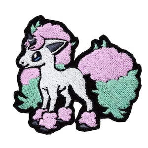 Puede incluir: Parche bordado de un unicornio blanco con pelo rosa y verde, de pie sobre sus patas traseras. El unicornio tiene ojos azules y un cuerno negro.