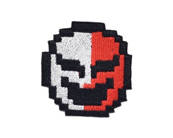 Puede incluir: Un parche bordado pixelado con un diseño de calavera. La calavera es mitad blanca y mitad roja.