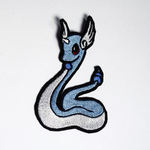 May include: A blue and white embroidered patch of a mythical creature with a horn and wings. The creature is curled up in a snake-like position.