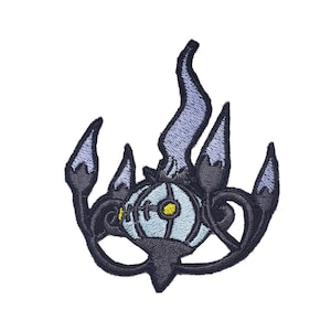 Könnte beinhalten: Gestickter Bügel-Patch mit einer schwarzen und lilafarbenen Cartoon-Figur mit einem weißen und gelben Auge. Die Figur ist von Flammen umgeben.