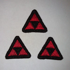 Puede incluir: Tres parches de hierro bordados de color rojo y negro en forma de triángulo con un triángulo más pequeño en el interior.