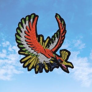 May include: Embroidered patch of a red, yellow, and green mythical bird with black outlines. The bird is in flight with its wings spread wide.
