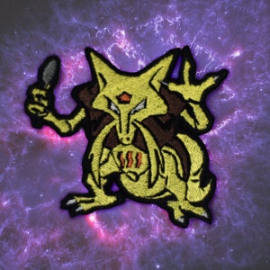 May include: Embroidered patch featuring a yellow creature with brown accents, holding a spoon-like object. The design includes a detailed face and chest markings. The patch is set against a purple and white galaxy background.