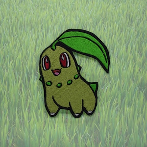 May include: Green and red embroidered patch of a cartoon Pokemon character with a leaf on its head.