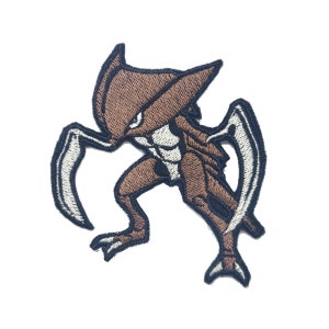 Pode incluir: Patch bordado com uma criatura marrom semelhante a um inseto com detalhes em branco e preto. O patch tem um design detalhado com uma aparência estilizada, adequado para aplicação em roupas ou acessórios. A criatura é retratada em uma pose dinâmica.