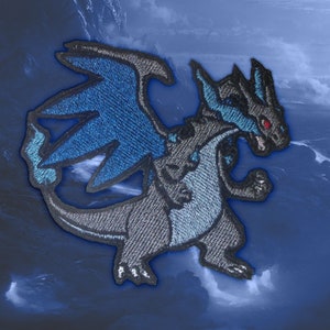 May include: An embroidered patch featuring a dragon-like Pokemon character in blue and grey with red eyes. The character is standing on its hind legs with its wings outstretched.