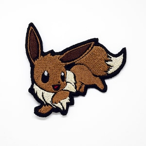 May include: Brown and cream embroidered patch of a cartoon Eeveelution Pokemon, with a brown body, cream fur, and brown ears.