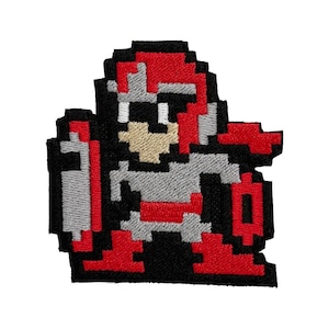 May include: Embroidered patch featuring a pixelated video game character in a fighting stance. The character is primarily red, gray, and black, with a shield and helmet. The patch is designed with a retro 8-bit aesthetic, perfect for jackets, bags, or other fabric items.