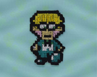 Jeff - Strykmärke - Glänsande metalliskt broderat. Jordnära märke.