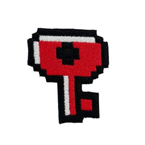 May include: A pixelated key patch with a red head, black outline, and white and black details. The key's stem is white with a black outline. The patch is likely for clothing or accessories.