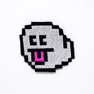 May include: A white pixelated ghost with black outlines and a pink tongue sticking out. The ghost has two black eyes.