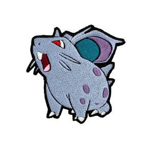 May include: A blue and purple embroidered patch of a cartoon Pokemon character with a large ear and spots.