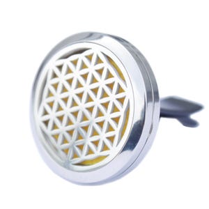 May include: Silver car air freshener with a flower of life design. The air freshener is round and has a clip on the back to attach to a car vent.