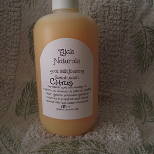 May include: A clear amber bottle of Aja's Naturals goat milk foaming facial wash in Citrus. The bottle is labelled with the ingredients: goat milk, coconut oil, rice bran oil, avocado oil, palm oil, purified water, glycerin, potassium hydroxide, rosemary & grapefruit seed extract, coconut milk, rose water, mineral salt. The bottle is 12 fl oz and made in Shallotte, NC.