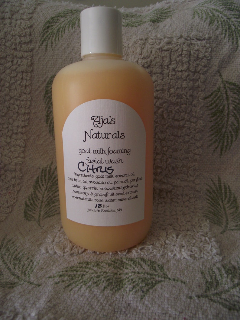 May include: A clear amber bottle of Aja's Naturals goat milk foaming facial wash in Citrus. The bottle is labelled with the ingredients: goat milk, coconut oil, rice bran oil, avocado oil, palm oil, purified water, glycerin, potassium hydroxide, rosemary & grapefruit seed extract, coconut milk, rose water, mineral salt. The bottle is 12 fl oz and made in Shallotte, NC.