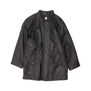 May include: A black leather jacket featuring a high collar, a front zipper closure concealed by a snap-button placket, two zippered chest pockets, and two lower flap pockets with snap closures. The jacket has long sleeves and a structured fit.